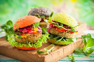 Drei fertig angerichtete Hamburger, appetitlich auf einer Holzplatte serviert.